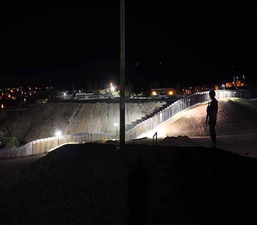 NOGALES, AZ - JUNE 22: A U.S. Army National Guardsman watches over the U.S.-Mexico border fence on June 22, 2011 in Nogales, Arizona. The Pentagon recently extended the deployment of some 1,200 guardsmen who were deployed last year to assist with border security on the U.S.-Mexico border until September 30. Soldiers at Early Identification Team (EIT) observation posts in Nogales work 24 hour shifts, each taking turns resting for 4 hours during the night. The National Guard troops are strictly on surveillance duty, although they are armed and have been credited with helping U.S. Border Patrol agents arrest up to 17,000 illegal immigrants crossing into the United States. (Photo by John Moore/Getty Images)