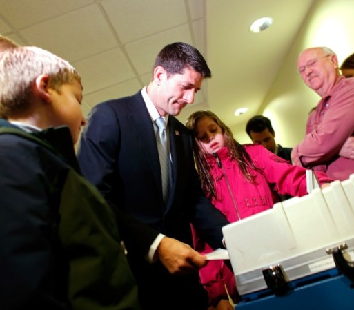Ryan coloca su voto en la urna, mientras su hija lo observa.