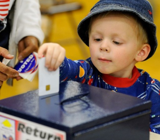 En Las Vegas, Zackary Lea, de 3 años, regresa la tarjeta de autorización después de que su madre emitiera su voto.