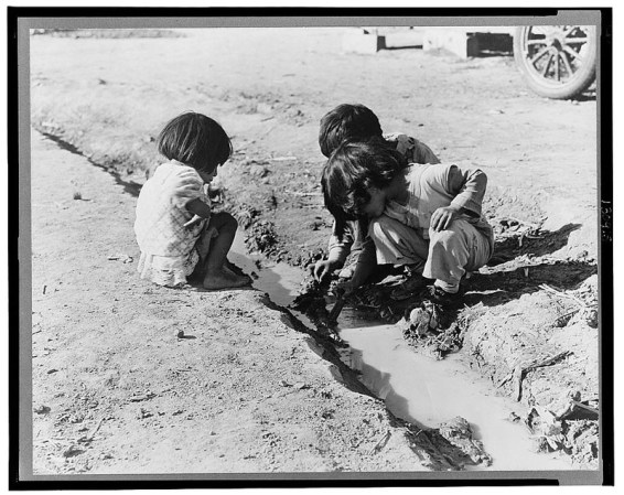 Niños mexicanos jugando en la zanja que atraviesa el campo de algodón compañía cerca de Corcoran, California.