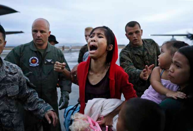 TACLOBAN, PHILIPPINES - NOVEMBER 12: An evacuee cries for a relative while boarding a US military evacuation flight at the airport in Tacloban in the aftermath of Typhoon Haiyan on November 12, 2013 in Tacloban, Leyte, Philippines. Typhoon Haiyan, packing maximum sustained winds of 195 mph (315 kph), slammed into the southern Philippines and left a trail of destruction in multiple provinces, forcing hundreds of thousands to evacuate and making travel by air and land to hard-hit provinces difficult. Around 10,000 people are feared dead in the strongest typhoon to hit the Philippines this year. (Photo by Kevin Frayer/Getty Images)