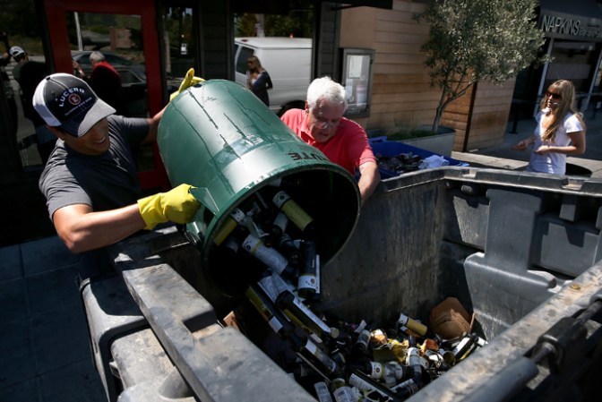 Empleados tiran botellas rotas en un contenedor de basura en Napa.