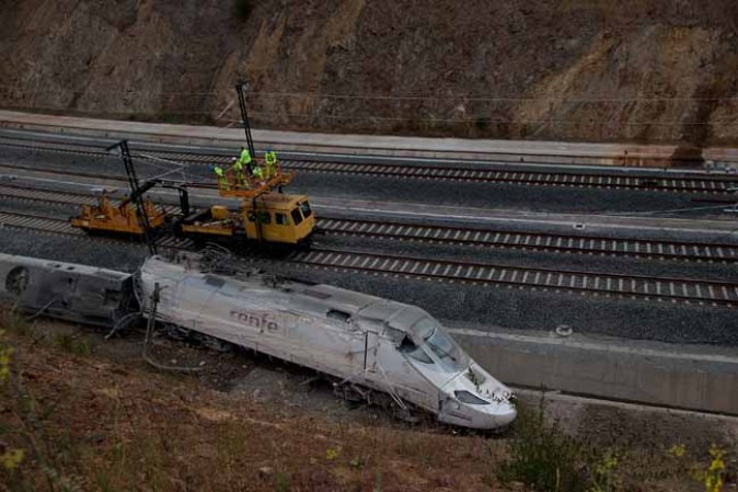 SANTIAGO DE COMPOSTELA, SPAIN - JULY 25: Operators work at the scene of a train crash on July 25, 2013 at Angrois near Santiago de Compostela, Spain. The crash occurred on Wednesday at 8.40pm as the train approached the north-western Spanish city of Santiago de Compostela, with 247 passengers on board. At least 77 people have died and a further 131 have been reported injured. The crash occurred on the eve of Santiago de Compostela's main religious festival, which has been cancelled by the City's officials. (Photo by Pablo Blazquez Dominguez/Getty Images)