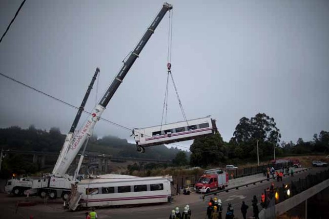 SANTIAGO DE COMPOSTELA, SPAIN - JULY 25: A carriage is lifted at the scene of a train crash on July 25, 2013 at Angrois near Santiago de Compostela, Spain. The crash occurred on Wednesday at 8.40pm as the train approached the north-western Spanish city of Santiago de Compostela, with 247 passengers on board. At least 77 people have died and a further 131 have been reported injured. The crash occurred on the eve of Santiago de Compostela's main religious festival, which has been cancelled by the City's officials. (Photo by Pablo Blazquez Dominguez/Getty Images)