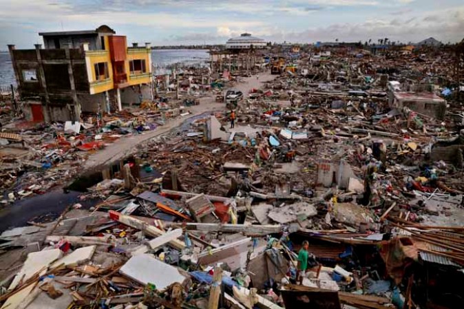 TACLOBAN, PHILIPPINES - NOVEMBER 13: Residents search through rubble amid scenes of devastation in the aftermath of Typhoon Haiyan on November 13, 2013 in Tacloban, Leyte, Philippines. Typhoon Haiyan, packing maximum sustained winds of 195 mph (315 kph), slammed into the southern Philippines and left a trail of destruction in multiple provinces, forcing hundreds of thousands to evacuate and making travel by air and land to hard-hit provinces difficult. Around 10,000 people are feared dead in the strongest typhoon to hit the Philippines this year. (Photo by Kevin Frayer/Getty Images)