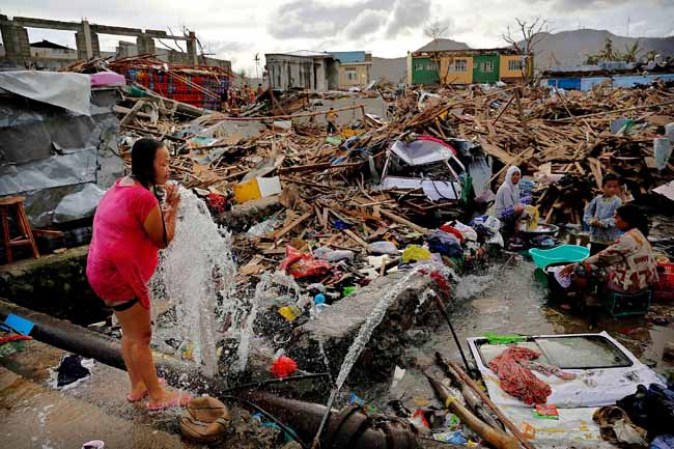TACLOBAN, PHILIPPINES - NOVEMBER 13: A woman washes amid scenes of devastation in the aftermath of Typhoon Haiyan on November 13, 2013 in Tacloban, Leyte, Philippines. Typhoon Haiyan, packing maximum sustained winds of 195 mph (315 kph), slammed into the southern Philippines and left a trail of destruction in multiple provinces, forcing hundreds of thousands to evacuate and making travel by air and land to hard-hit provinces difficult. Around 10,000 people are feared dead in the strongest typhoon to hit the Philippines this year. (Photo by Kevin Frayer/Getty Images)