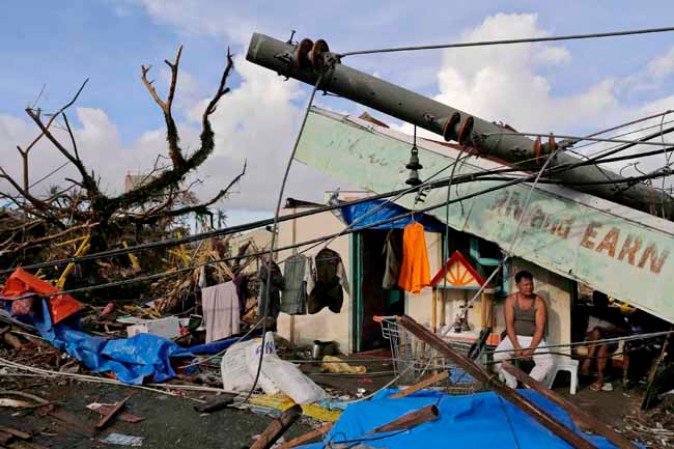 TACLOBAN, PHILIPPINES - NOVEMBER 13: A man sits in front of his destroyed business amid scenes of devastation in the aftermath of Typhoon Haiyan on November 13, 2013 in Tacloban, Leyte, Philippines. Typhoon Haiyan, packing maximum sustained winds of 195 mph (315 kph), slammed into the southern Philippines and left a trail of destruction in multiple provinces, forcing hundreds of thousands to evacuate and making travel by air and land to hard-hit provinces difficult. Around 10,000 people are feared dead in the strongest typhoon to hit the Philippines this year. (Photo by Kevin Frayer/Getty Images)