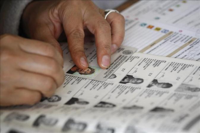 Un funcionario de casilla busca el nombre de una electora.