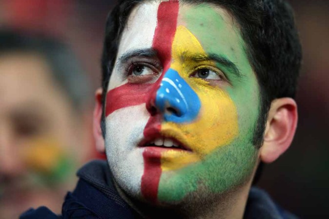 Un fanático del fútbol divide su rostro en dos. Asiste a un encuentro entre Brasil e Inglaterra.