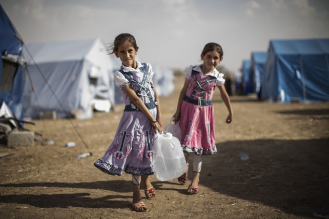 KALAK, IRAQ Niños iraquis refugiados llevando agua a sus tiendas.