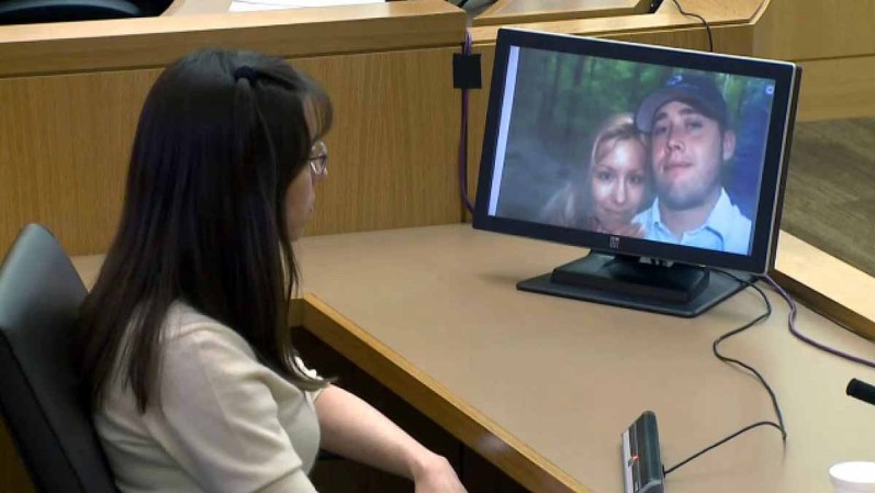 En esta foto tomada en la corte, Arias observa una de sus imágenes con Travis Alexander