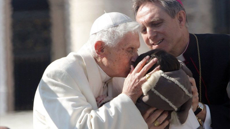 Papa Benedicto XVI le da un beso a un niño antes de irse de la plaza de San Pedro en el Vaticano.