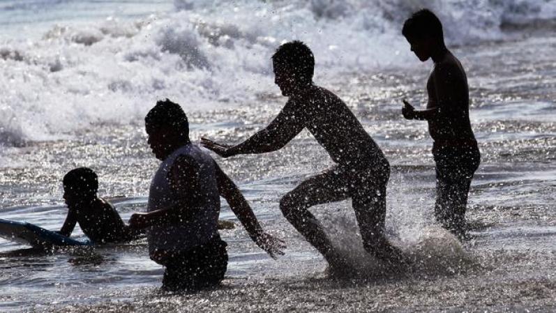 Niños juegan en las olas de lo que alguna vez fue el paraíso de México.