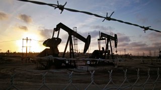 the sun sets beyond pumpjacks operating at the Inglewood oil fields in the Baldwin Hills area of Los Angeles