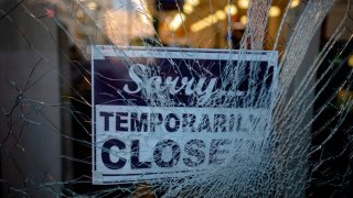 A broken window with a sign hanging that reads "Sorry temporarily closed."