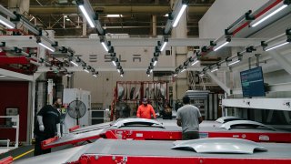 Tesla employees work to finish the upper rear trunk of the Tesla Model 3