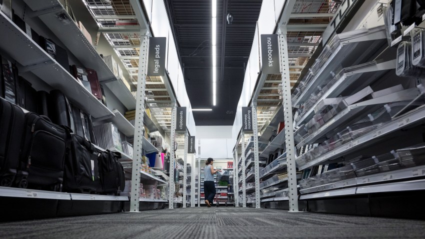 A customer pushes a cart through an Office Depot store.