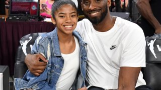 Kobe and Gianna Bryant hugging, smiling at the camera sitting down