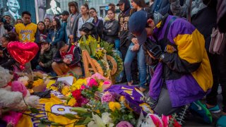 People gather around a makeshift memorial for former NBA and Los Angeles Lakers player Kobe Bryant after learning of his death, at LA Live plaza in front of Staples Center in Los Angeles, Jan. 26, 2020.