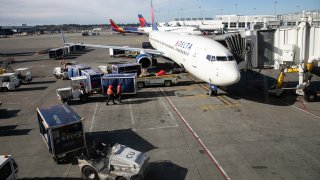A ground crew prepares to unload luggage from an arriving Delta Airlines flight