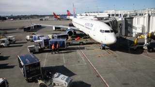 A ground crew prepares to unload luggage from an arriving Delta Airlines flight
