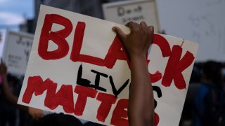 A person holds up a placard that reads, 'Black lives matter'