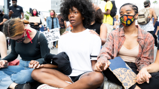 Demonstrators sit holding hands during a march in response to George Floyd's death on June 2, 2020 in Los Angeles.