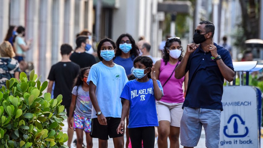 A family wearing facemasks walks at a shopping centre in Miami Beach, Florida on June 29, 2020. – The City of Miami issued an emergency order mandating facial coverings be worn in public at all times and until further notice. Officials will start issuing fines of up to $500 for not wearing a mask in public. (Photo by CHANDAN KHANNA / AFP) (Photo by CHANDAN KHANNA/AFP via Getty Images)