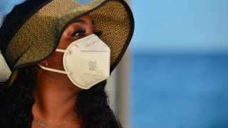 A beach-goer wears a face mask on the beach after a mandate to wear face masks in public spaces went into effect on Tuesday June 30, 2020 in Miami Beach, Florida