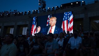 U.S. President Donald Trump is displayed on a screen as he speaks during an event at Mount Rushmore National Memorial in Keystone, South Dakota, U.S., on Friday, July 3, 2020. The early Independence Day celebration, which will feature a military flyover and the first fireworks in more than a decade, is expected to include about 7,500 ticketed guests who won't be required to wear masks or socially distance despite a spike in U.S. coronavirus cases.