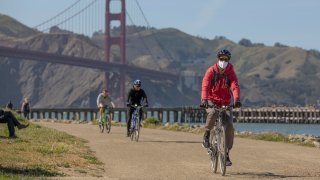 In this April 27, 2020, file photo, people ride bicycles near the Golden Gate Bridge amid the coronavirus outbreak in San Francisco, California.
