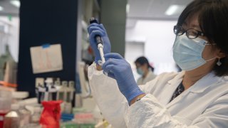 In this May 22, 2020, file photo, Bonghui Li works in a lab that is focused on fighting COVID-19 at Sorrento Therapeutics in San Diego, California.