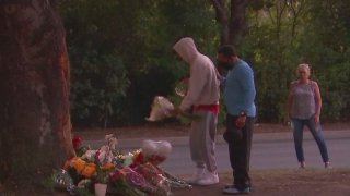 Mourners leave flowers at a memorial.