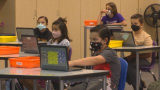 Children wear masks while sitting in a classroom