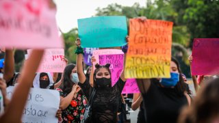 Grupo de mujeres muestran carteles de protesta