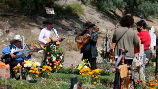 Grupo de músicos interpreta canciones frente a tumbas