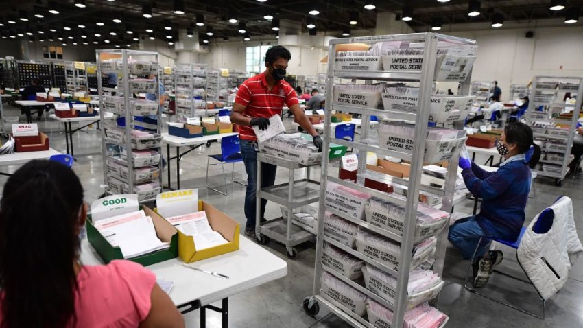 An election worker delivers mail-in ballots to workers who will examine and verify the ballots to prepare them for tabulation at the Los Angeles County Registrar Recorders’ mail-in ballot processing center at the Pomona Fairplex in Pomona, California, October 28, 2020. – Officials relocated mail-in ballot processing to the expansive location due to the need for COVID-19 social distancing for the ballot workers and the large number of mail-in ballots. While the tabulation of votes cast for Donald Trump and Joe Biden will begin when polls close on November 3 at 8pm, envelopes are now being sorted and signatures and ballots verified to expedite the tabulation process on November 3. (Photo by Robyn Beck / AFP) (Photo by ROBYN BECK/AFP via Getty Images)