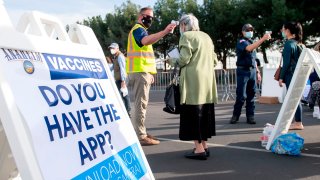 People have their temperature checked as they arrive at a Disneyland parking lot.