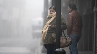Dos personas en la calle envuelta en bruma por frío