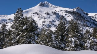 The mountains and trees along Highway 50 are covered in snow.