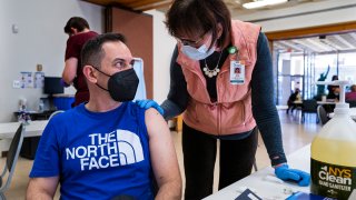 Marx Johny Gerez, of Binghamton, N.Y., who was living in Venezuela until just over a year ago, speaks with Physician Assistant Judy Andrews before receiving a COVID-19 vaccine at a pop-up clinic at the American Civic Association (ACA) in Binghamton