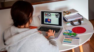 Una joven hace un dibujo frente a una laptop