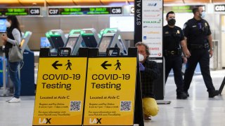 Un viajero toma una foto de un letrero de prueba de Covid-19 en la Terminal Internacional Tom Bradley (TBIT) en medio de restricciones de viaje durante la pandemia de Covid-19 en el Aeropuerto Internacional de Los Ángeles (LAX) el 4 de febrero de 2021 en Los Ángeles, California.