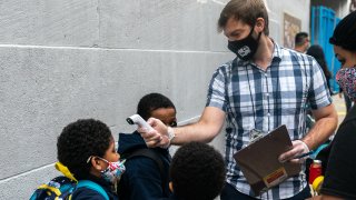 Teacher performs temperature check on student