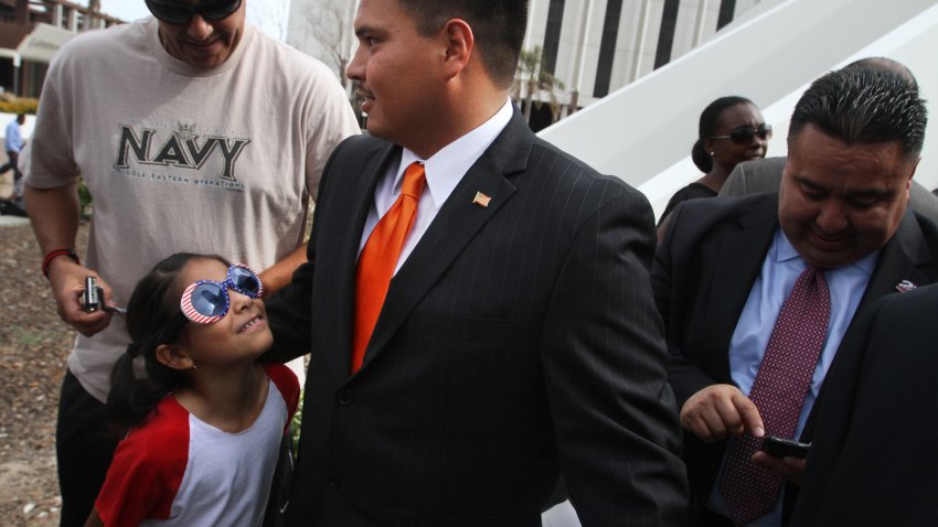 New Compton city councilman Isaac Galvan, center gets congratulations from Gary Valencia, left and his daughter Sydney after he was sworn in on JULY 02, 2013.   Galvan, the first Latino to serve as a city councilman in Compton, lived with the Valencias for a time when he was growing up.  (Photo by Bob Chamberlin/Los Angeles Times via Getty Images)