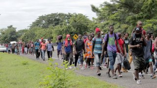 Grupo de personas migrantes, en su mayoría de Haití, caminan por una carrera del sureste de México