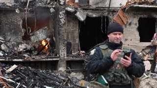 Un oficial de policía hace guardia en un edificio residencial dañado en la calle Koshytsa, un suburbio de la capital ucraniana, Kiev, donde supuestamente cayó un proyectil militar el 25 de febrero de 2022.