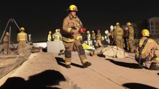 Firefighters on the roof of a Koreatown apartment building rescue a woman from a trash chute.