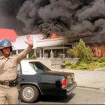 A California Highway patrolman directs raffic around a shopping center engulfed in flames in Los Angeles.