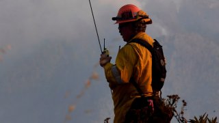 A firefighter keeps an eye on fires from a ridge.